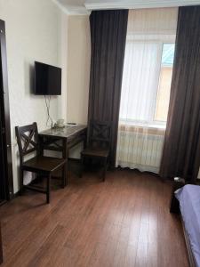 a room with a table and chairs and a window at Посейдон ЖМ Амангельды ул Тепличная 4 in Kostanay