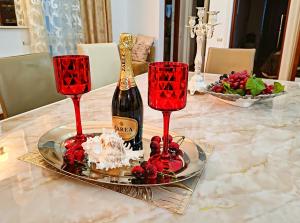 a bottle of champagne and two red wine glasses on a table at Elisa Summerland Apartment in Mamaia