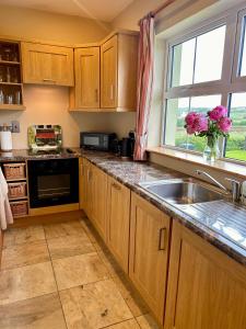 a kitchen with wooden cabinets and a sink and a window at Fairy Fort View, Lahinch in Carrowauff