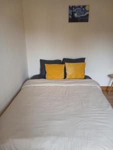 a bed with two yellow pillows on top of it at Sérénité in Corquilleroy