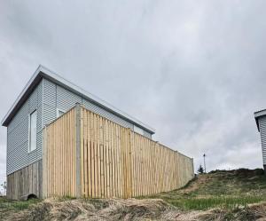 a wooden building on a hill next to a fence at New listing - Krosshóll Cottage, built in 2026 in Hella