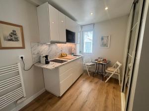 a kitchen with white cabinets and a sink and a table at La suite de Elise in Beaulieu-sur-Mer