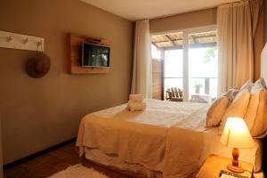 a bedroom with a bed with a tv and a window at Le Terrace in Morro de São Paulo