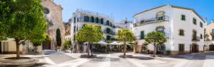 a street in a town with trees and buildings at L´Hostalet in Tossa de Mar
