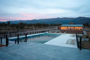 a swimming pool with a building and mountains in the background at Takuá Hotel Serrano in La Punta