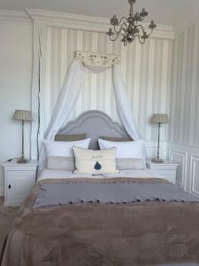 a white bedroom with a large bed with a canopy at Villa Celine in Mielno