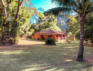 a house with a palm tree in front of a yard at Casa aconchego Secretário in Araras Petropolis