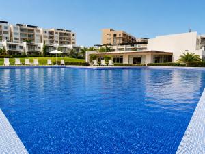a large swimming pool with blue water in front of buildings at Casa Vista 133 in Cabo San Lucas