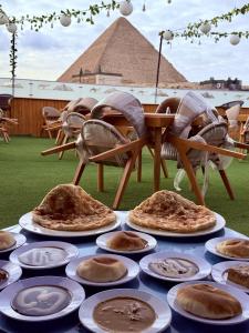 a table with plates of pizza on it with a pyramid in the background at Sunshine Pyramids Hotel & Restaurant in Cairo