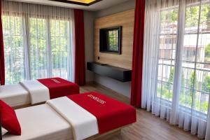 two beds in a room with large windows at Sezgin Hotel in Uzungöl