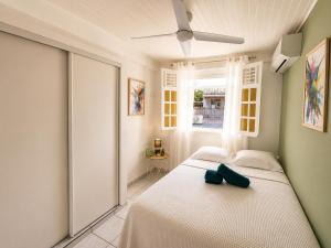 a bedroom with a white bed and a window at Villa Coralys - Plage - Cozy in Schœlcher