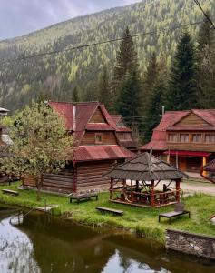 a group of wooden buildings and a river with benches at Smerekova Hata in Yablunytsya