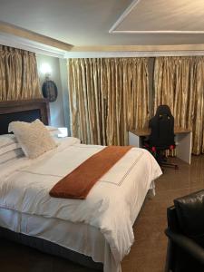 a bedroom with a bed and a desk and a chair at Silver Gates BnB in Mbabane