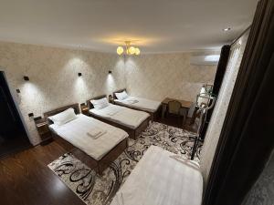 a room with three beds and a rug at Guest house Homely in Dushanbe