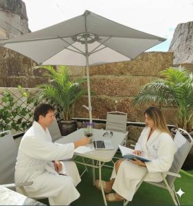 Ein Mann und eine Frau sitzen an einem Tisch unter einem Regenschirm in der Unterkunft Opus House in Guimarães