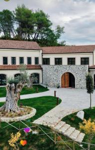 a large building with a tree in the yard at Mugull Agrotourism Hotel in Tirana