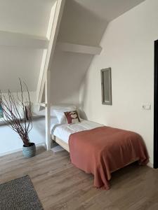 a bedroom with a bed in a white room at Atelier Onder de Notenboom in Appeltern