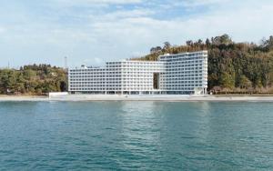 a large white building next to a body of water at Bamboo beach tsikhisdziri in Kobuleti