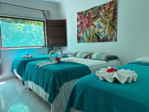 a room with three beds with blue sheets and a painting at Pousada Vôo da Águia in Itacaré +57 photos
