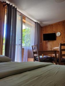 a bedroom with a bed and a desk and a window at Pod Sosnami 46 in Pobierowo