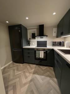 a kitchen with a black refrigerator and a wooden floor at Halden downtown apartment in Halden