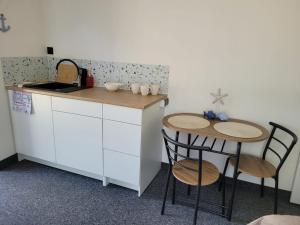 a kitchen with two chairs and a counter and a sink at Pod Sosnami 46 in Pobierowo