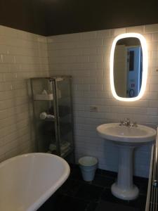 ein Badezimmer mit einem Waschbecken, einer Badewanne und einem Spiegel in der Unterkunft Baeten's bed and breakfast in Gent