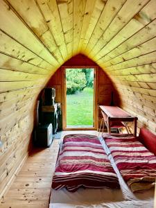 a large bed in a wooden room with a window at Chatka in Tappernøje