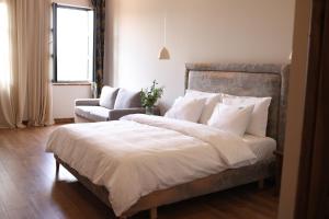 a bedroom with a large bed and a chair at Mugull Agrotourism Hotel in Tirana
