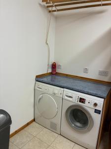 a washing machine in a laundry room with a counter at Lotties Neuk in Lerwick