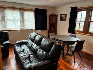 a living room with a leather couch and a table at Lotties Neuk in Lerwick +1 photo