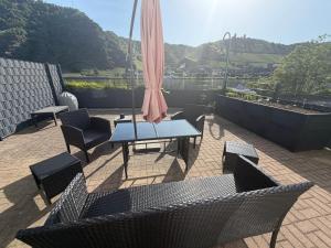 a patio with a table and chairs and an umbrella at Ferienwohnung Schöne Aussicht in Löf