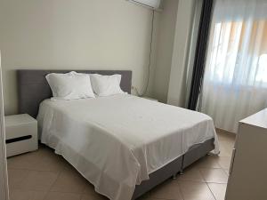 a bedroom with a bed with white sheets and a window at Garden view apartment in Karpen