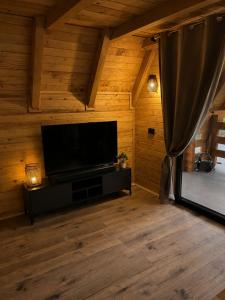 a living room with a flat screen tv on a wooden wall at Vikendica Ema in Šipovo