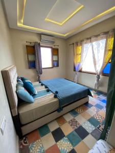 a bedroom with a bed with blue sheets and windows at Le domaine de Koujane in Oulad el Guern +3 photos