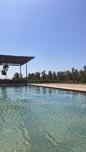 a pool of water with a pavilion on a beach at Le domaine de Koujane in Oulad el Guern