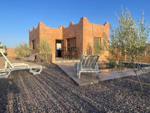 a house in the desert with two chairs on a deck at Le domaine de Koujane in Oulad el Guern