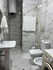 a white bathroom with a toilet and a sink at Garden view apartment in Karpen +4 photos