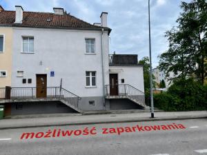 a white building with stairs on the side of a street at AT Apartament in Pasłęk