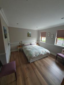 a bedroom with a large bed and two windows at Cnoc Sí 1 in Kilgarvan +1 photo