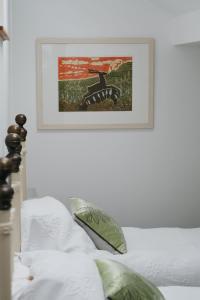 a picture hanging on a white wall above a bed at Little Woodacott in Barnstaple
