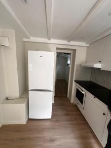 a kitchen with white cabinets and a white refrigerator at Abildsø Apartment in Oslo