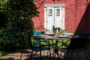 a table with four chairs in front of a red building at Les Airis, maison de vacances écologique in Avignon