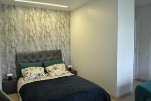 a bedroom with a black bed with a wall at Žemaičių g apartamentai in Kretinga