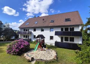 a white house with a playground in the yard at Tanne 16 - Bike & Familienurlaub in Braunlage in Braunlage