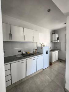 eine Küche mit weißen Schränken und einem weißen Kühlschrank in der Unterkunft Aloha 3 in Chacabuco