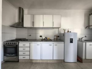 eine Küche mit weißen Schränken und einem Kühlschrank in der Unterkunft Aloha 3 in Chacabuco