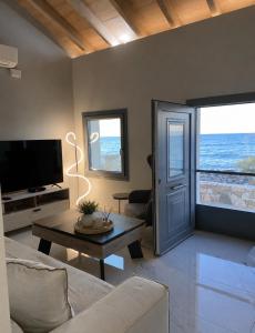 a living room with a couch and a tv and a door at Villa Harmonia II-Seafront Retreat in Livadáki