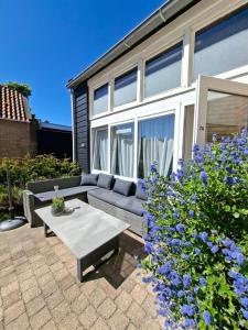 a patio with a couch and a table in front of a house at Dulce Tierra - vakantiewoning in Zoutelande