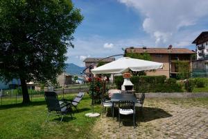 a table and chairs under an umbrella in a yard at Attic House Mountain Lake Iseo Hospitality in Bossico